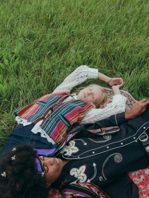 A couple in vibrant clothing relaxes on grass, showcasing a blend of cultures and harmony.